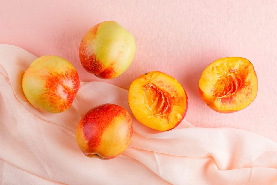 Nectarinas rodajas mesa rosa textil aplanada